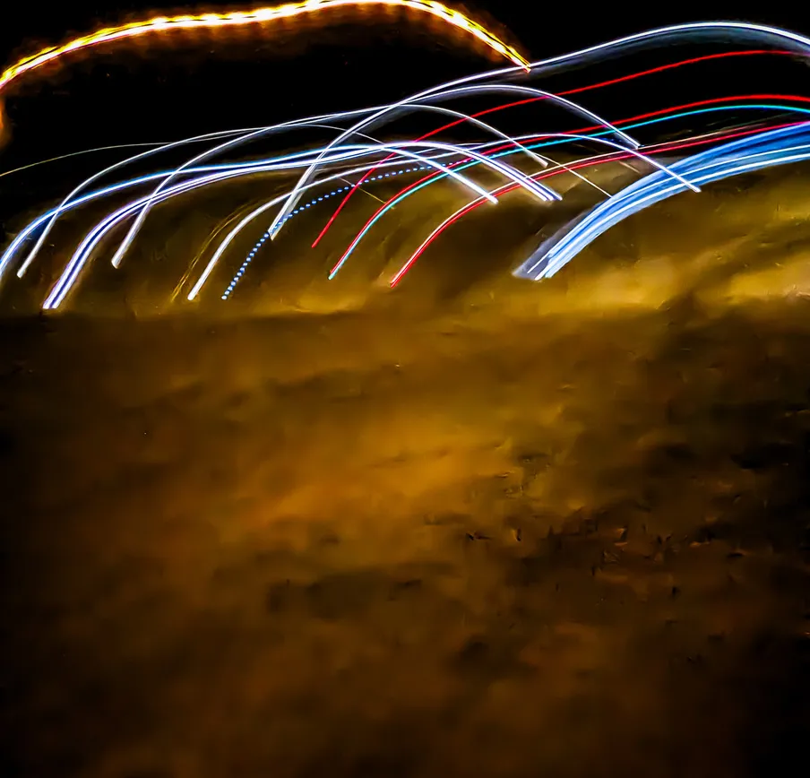 Arcos de oro: fotografía abstracta de luz en movimiento en tonos naranja y amarillo sobre fondo oscuro, serie Luz en movimiento, por Robert Díaz
