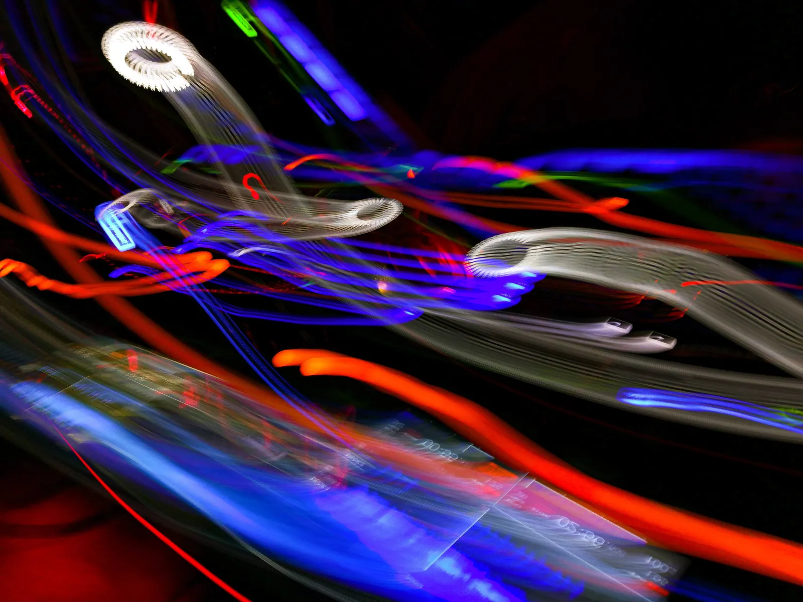 Cruce de cintas: fotografía abstracta de luz en movimiento en tonos azul y rojo sobre fondo oscuro, serie Luz en movimiento, por Robert Díaz