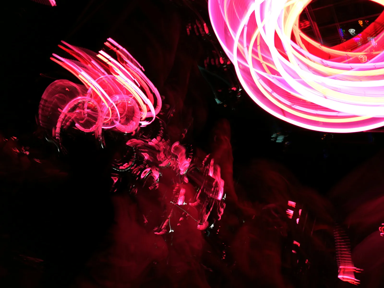 Flor de neón: fotografía abstracta de luz en movimiento en tonos rojo y magenta sobre fondo oscuro, serie Luz en movimiento, por Robert Díaz