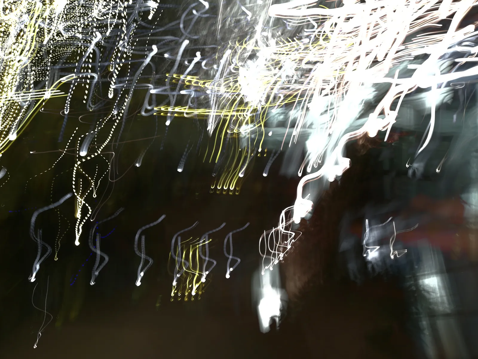 Lluvia de faros: fotografía abstracta de luz en movimiento en tonos amarillo y naranja sobre fondo oscuro, serie Luz en movimiento, por Robert Díaz