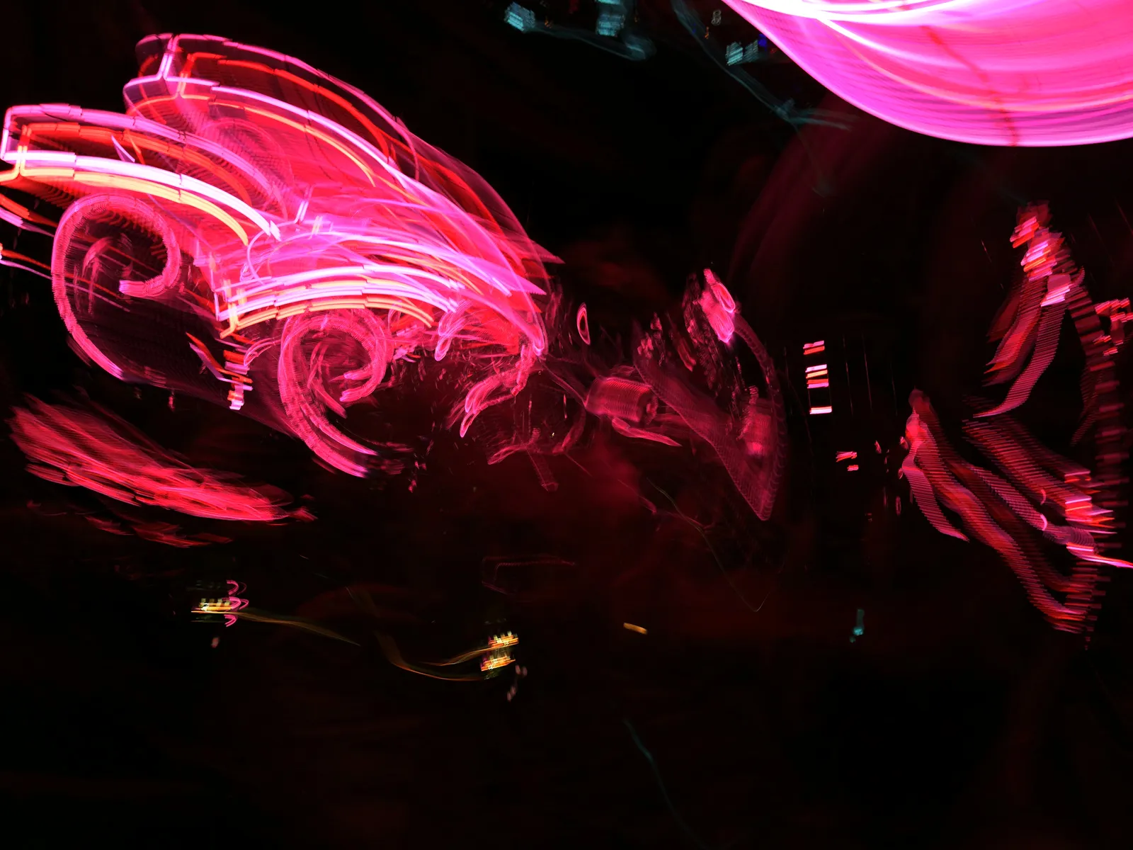 Neón entre sombras: fotografía abstracta de luz en movimiento en tonos rojo y magenta sobre fondo oscuro, serie Luz en movimiento, por Robert Díaz