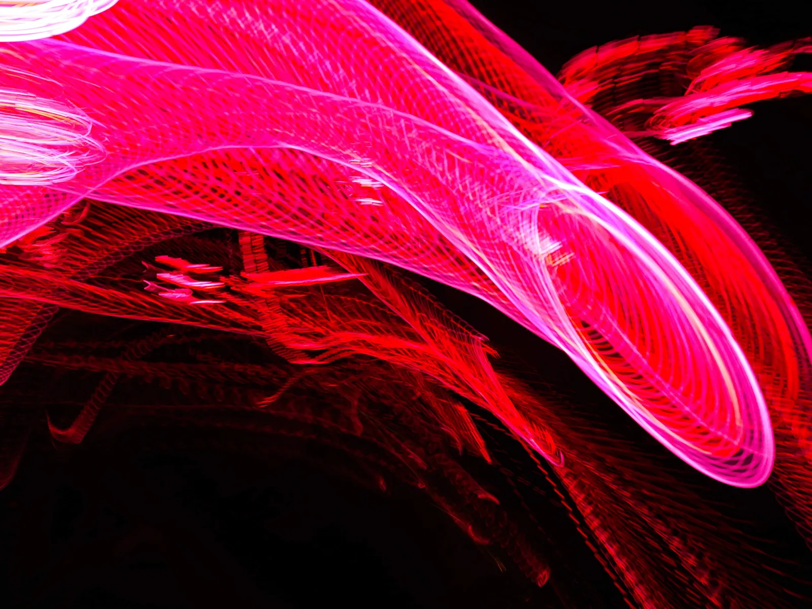 Ola magenta: fotografía abstracta de luz en movimiento en tonos magenta y rojo sobre fondo oscuro, serie Luz en movimiento, por Robert Díaz
