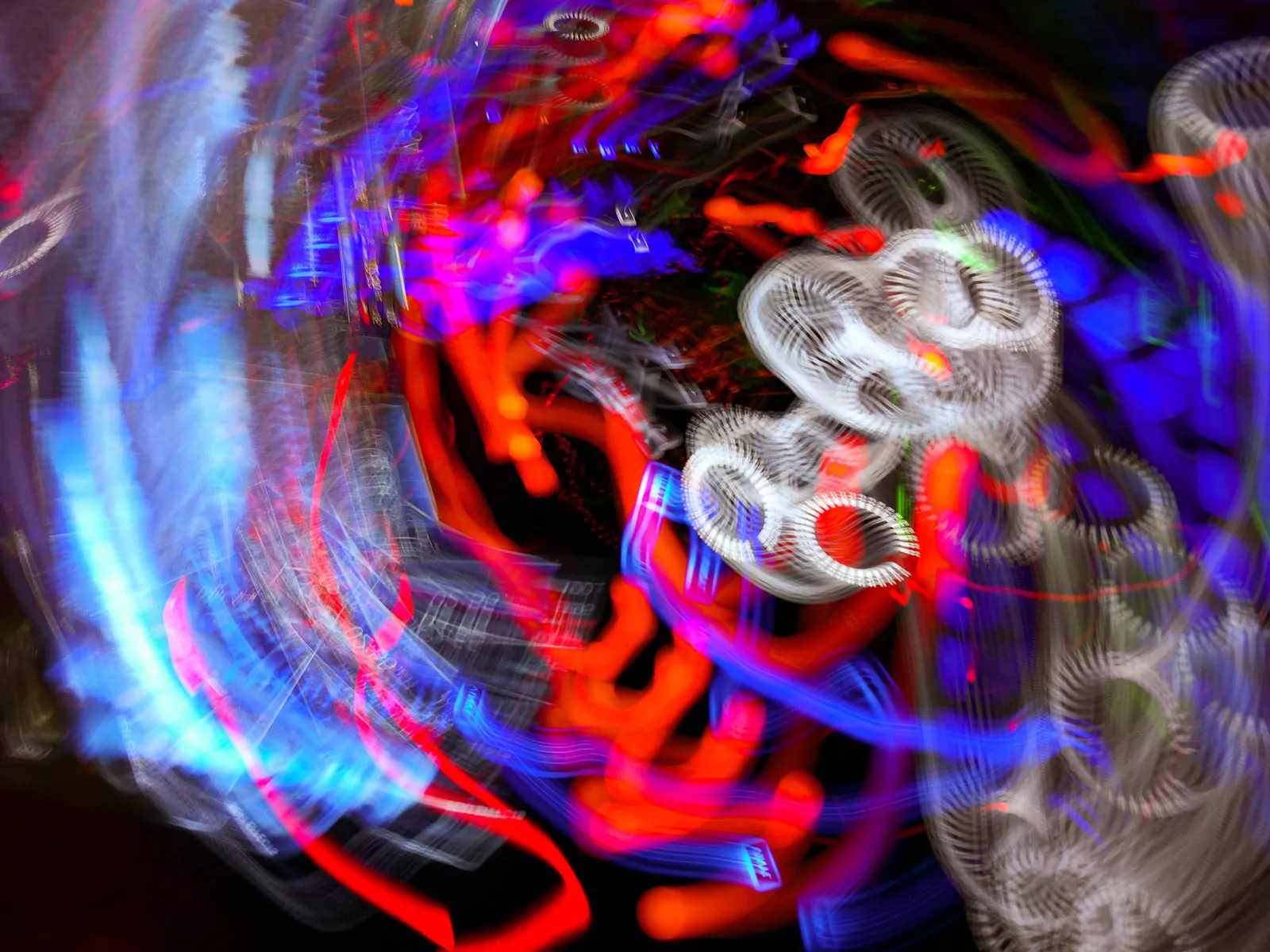 Torbellino: fotografía abstracta de luz en movimiento en tonos azul y rojo sobre fondo oscuro, serie Luz en movimiento, por Robert Díaz